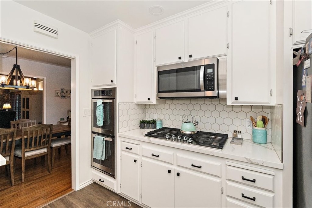 8530 Harmony Lane Riverside, CA 92504 - Photo 13 of 40 a kitchen with stainless steel appliances white cabinets and stove top oven