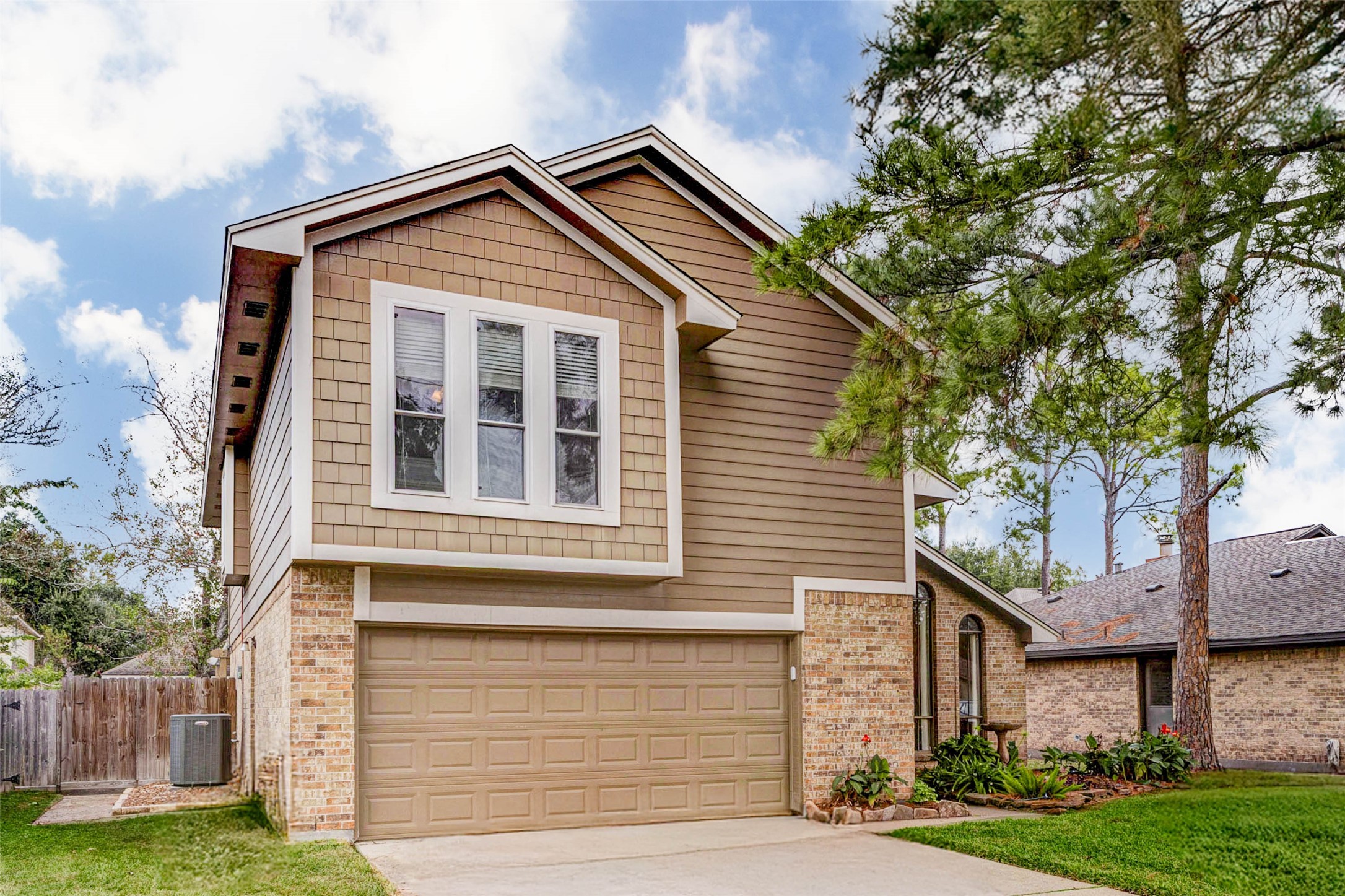 15811 Spring Forest Drive Houston, TX 77059 - Photo 2 of 27 Charming two-story home with a modern exterior featuring a mix of brick and siding. It includes a spacious two-car garage, a well-maintained driveway, and lush landscaping, set in a serene neighborhood with mature trees.