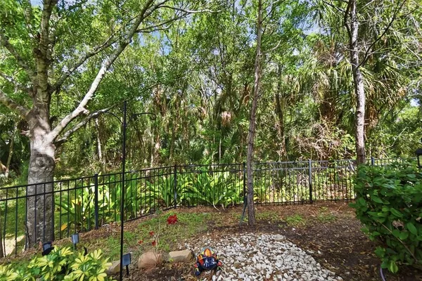 a backyard of a house with lots of plants and large trees