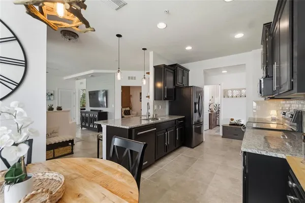 a kitchen with stainless steel appliances kitchen island granite countertop a sink refrigerator and cabinets