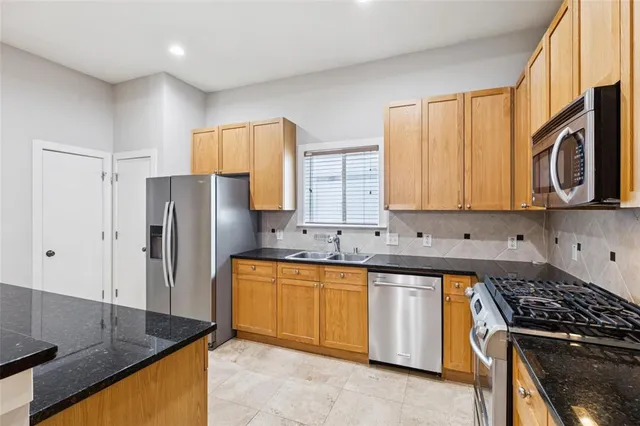 a kitchen with stainless steel appliances granite countertop a stove a refrigerator and a sink