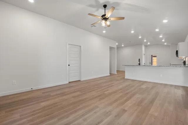 a view of an empty room with kitchen and a chandelier