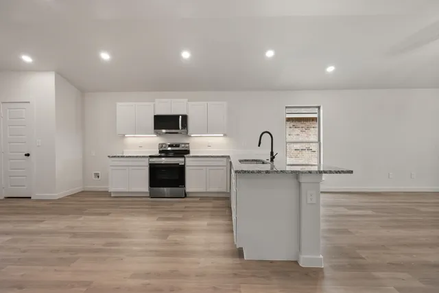 a kitchen with stainless steel appliances a refrigerator sink and white cabinets