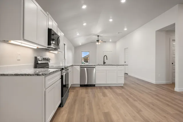 a kitchen with stainless steel appliances granite countertop a stove a sink and a refrigerator