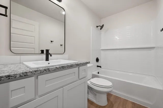 a bathroom with a granite countertop toilet a sink and a bathtub