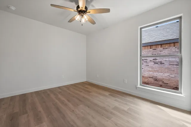an empty room with windows and fan