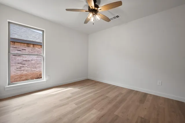 an empty room with a window and a fan