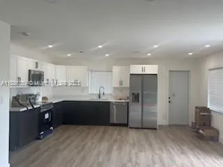 a large kitchen with stainless steel appliances granite countertop a refrigerator and a stove top oven