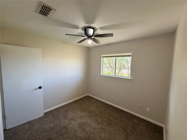 an empty room with a window and a ceiling fan