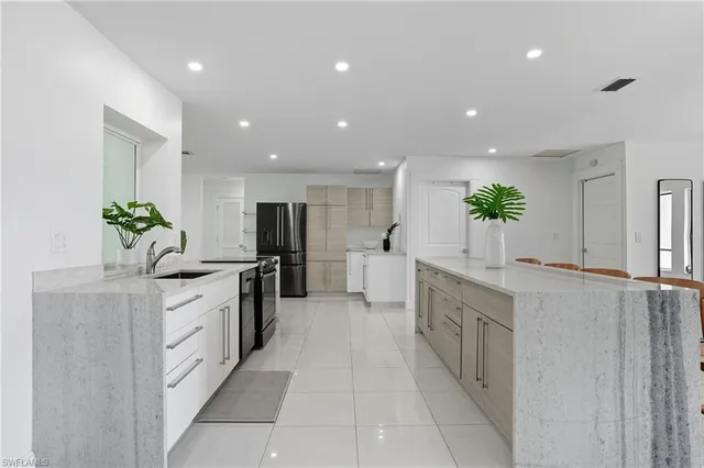 a large kitchen with stainless steel appliances a large counter top a sink and a stove