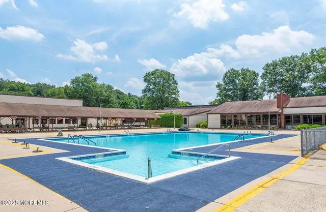 a view of swimming pool with outdoor seating and trees in the background