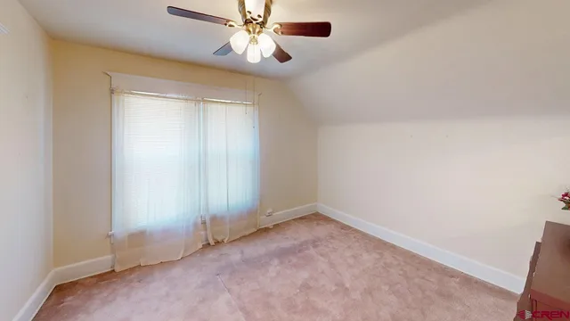 an empty room with a chandelier fan and windows