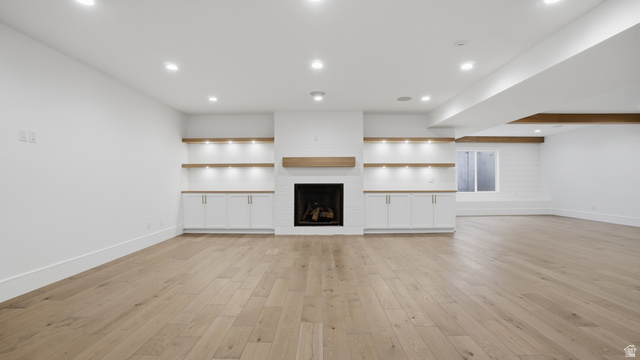 1682 North 1950 W Street, Unit 9 Provo, UT 84604 - Photo 43 of 84 Spacious room featuring light wood-finish flooring, a contemporary fireplace with a wood mantle, and built-in cabinetry with integrated shelving and lighting