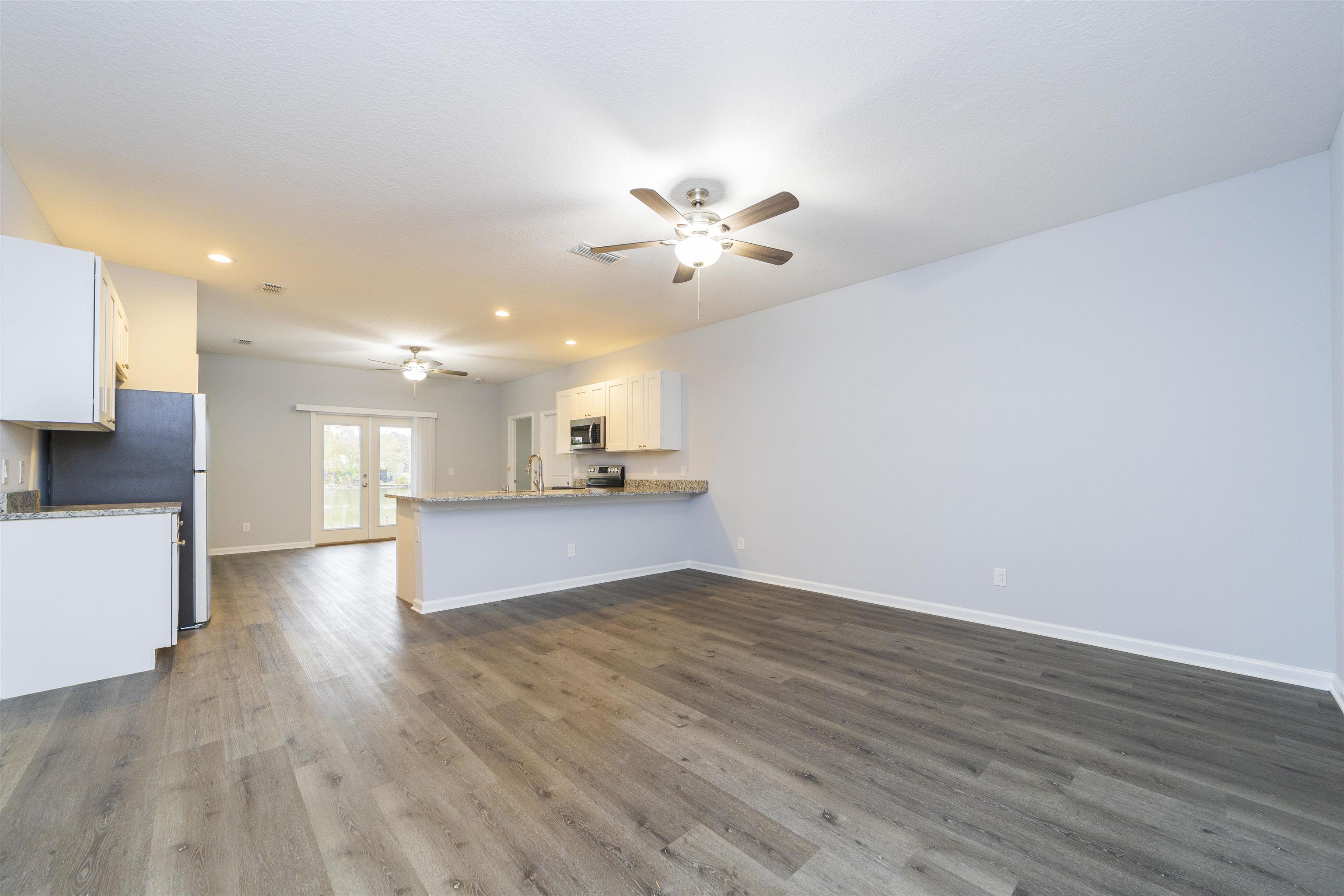 679 Coral Circle St. Augustine, FL 32080 - Photo 15 of 48 a view of an empty room and a kitchen with wooden floor