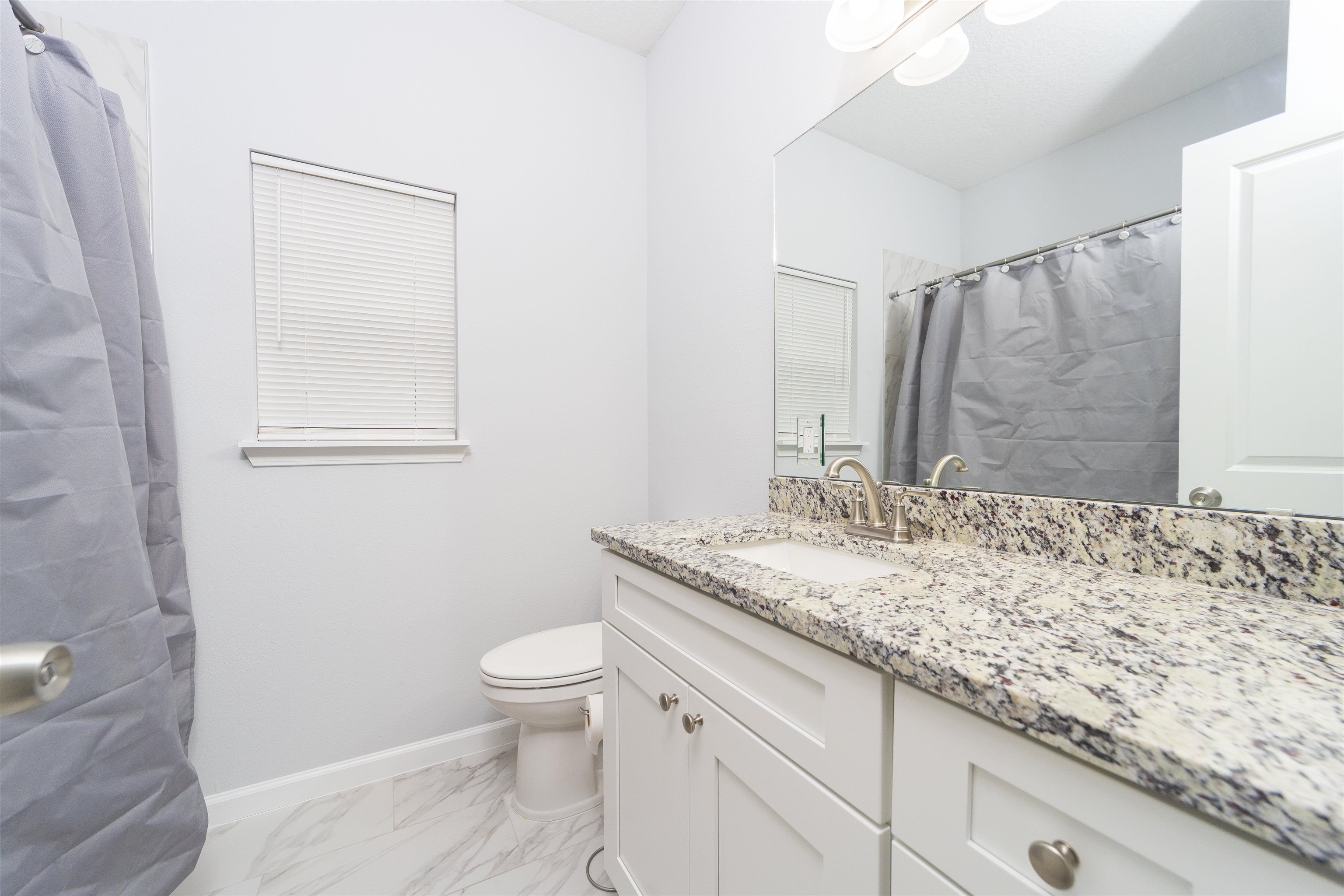 679 Coral Circle St. Augustine, FL 32080 - Photo 30 of 48 a bathroom with a granite countertop sink toilet and mirror