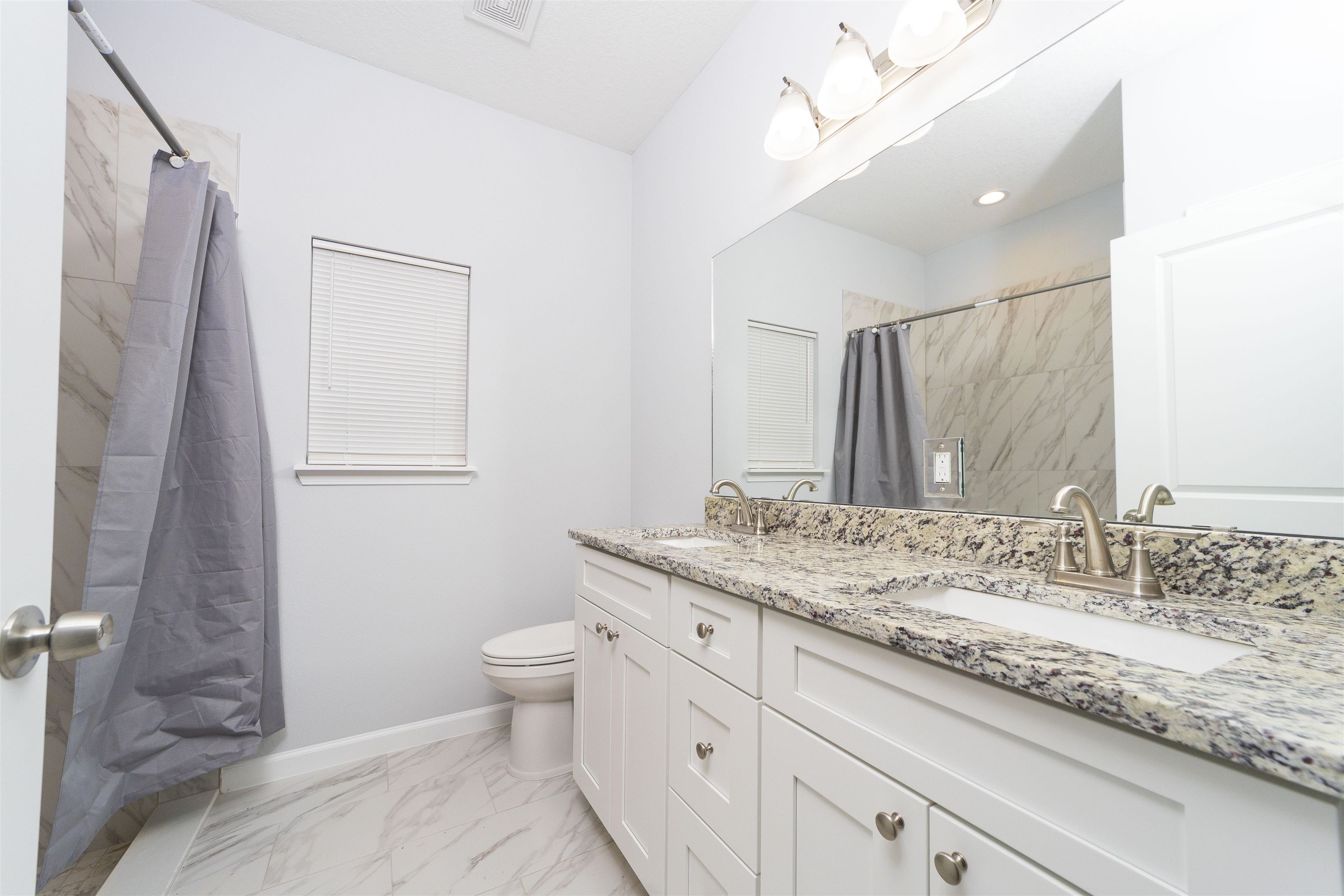 679 Coral Circle St. Augustine, FL 32080 - Photo 41 of 48 a bathroom with a granite countertop sink a toilet and a mirror