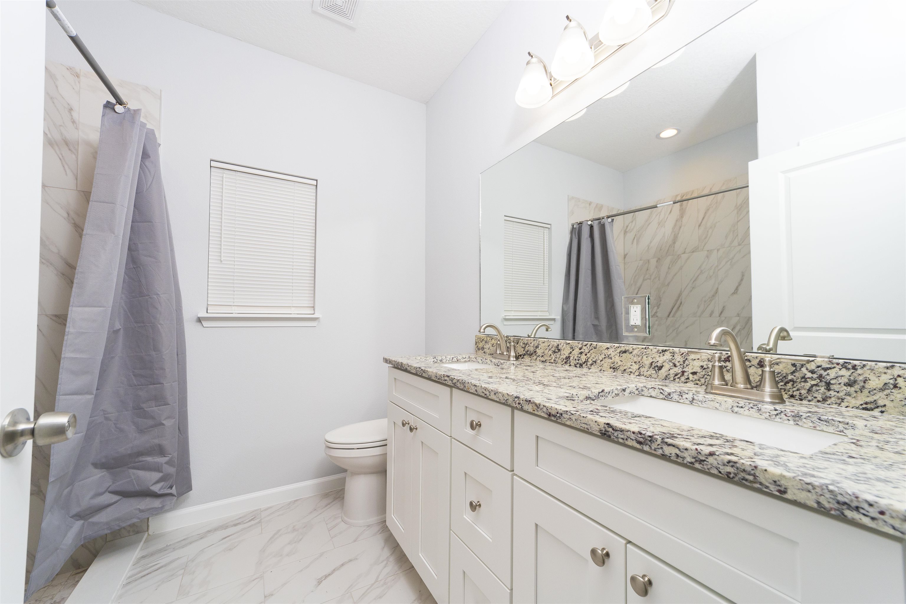 679 Coral Circle St. Augustine, FL 32080 - Photo 42 of 48 a bathroom with a granite countertop sink a toilet and a mirror