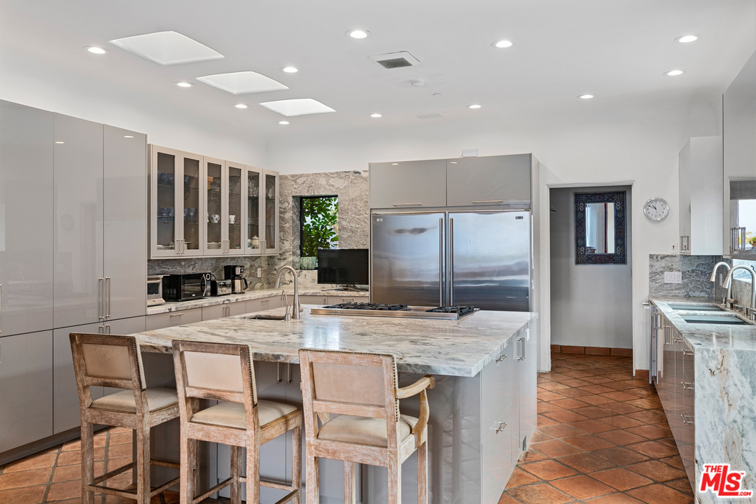 21424 Deerpath Lane Malibu, CA 90265 - Photo 15 of 51 a kitchen with stainless steel appliances granite countertop a kitchen island a stove a refrigerator and a sink