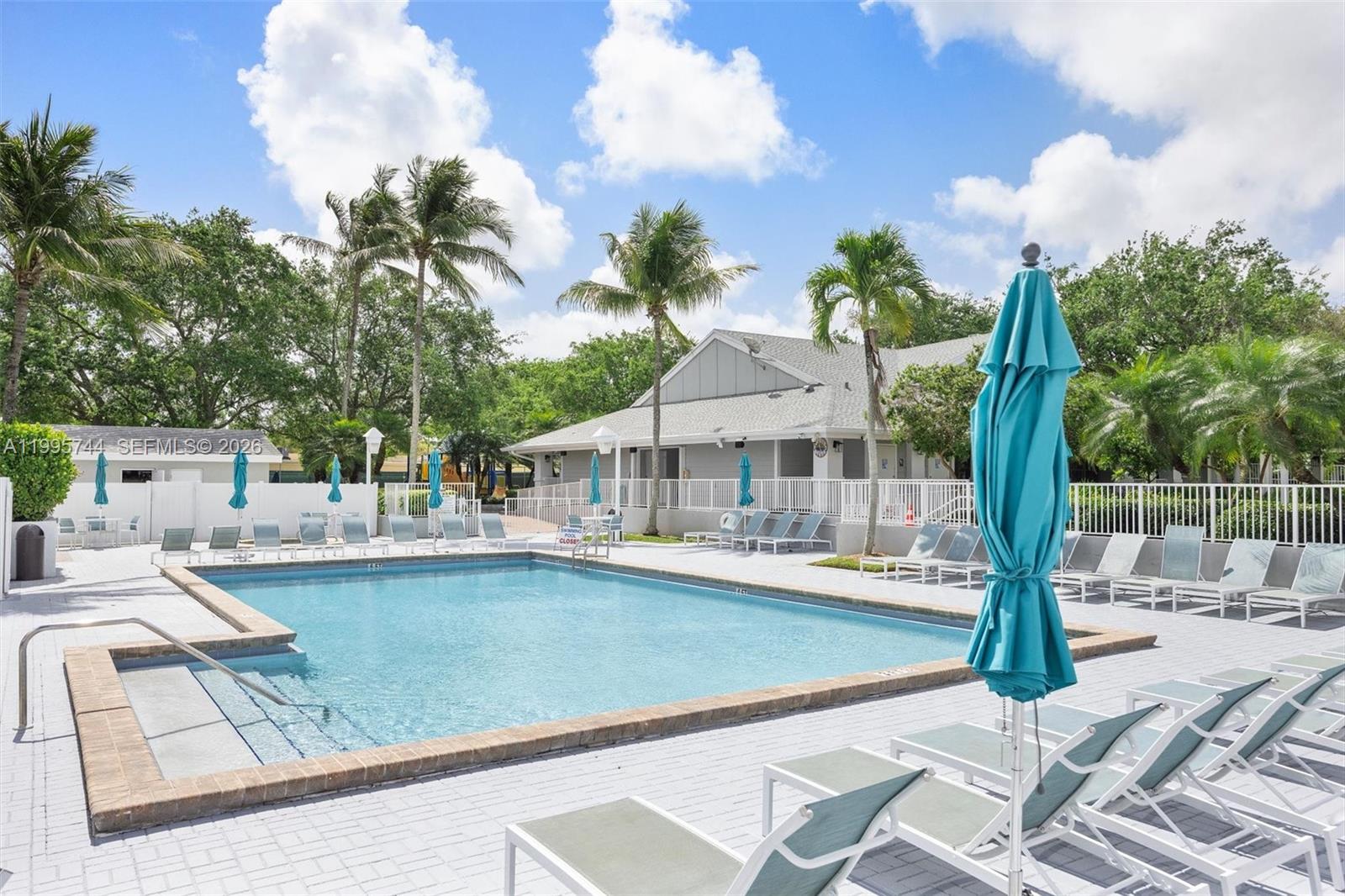 14720 Southwest 139th Avenue, Unit 139 Miami, FL 33186 - Photo 29 of 34 a front view of a house with swimming pool and glass top table and chairs