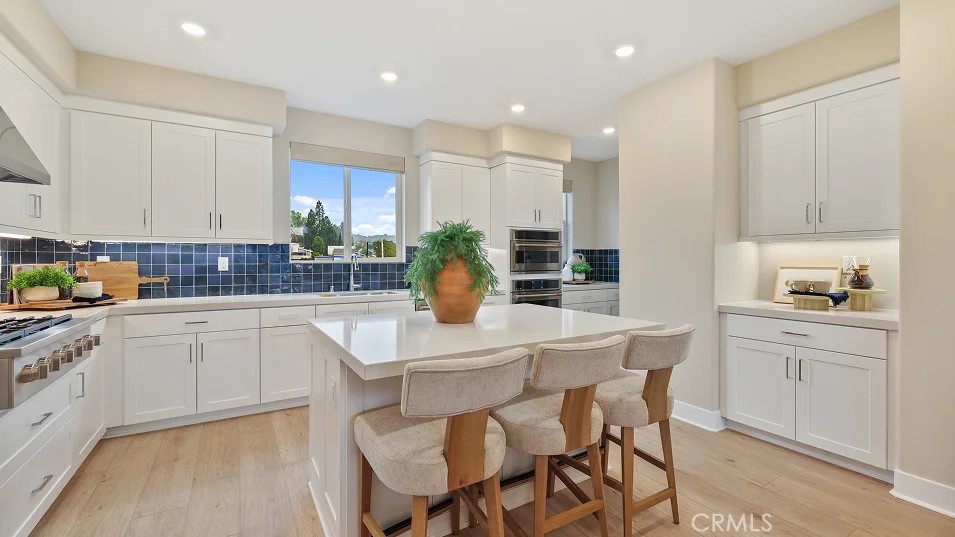 a kitchen with stainless steel appliances kitchen island granite countertop a table chairs sink and cabinets