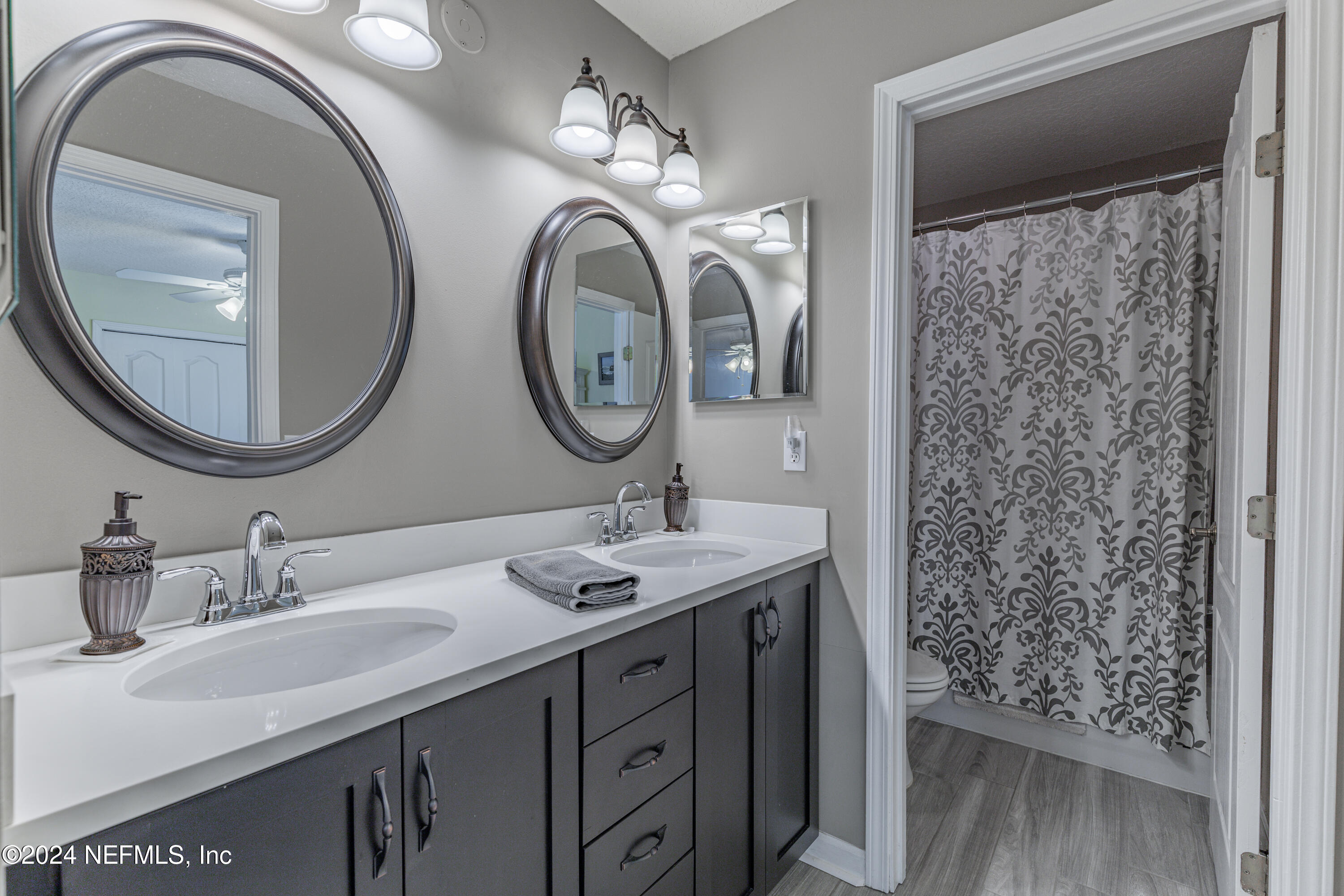 1830 Copper Stone Drive, Unit D Fleming Island, FL 32003 - Photo 26 of 65 a bathroom with a sink a mirror and a toilet