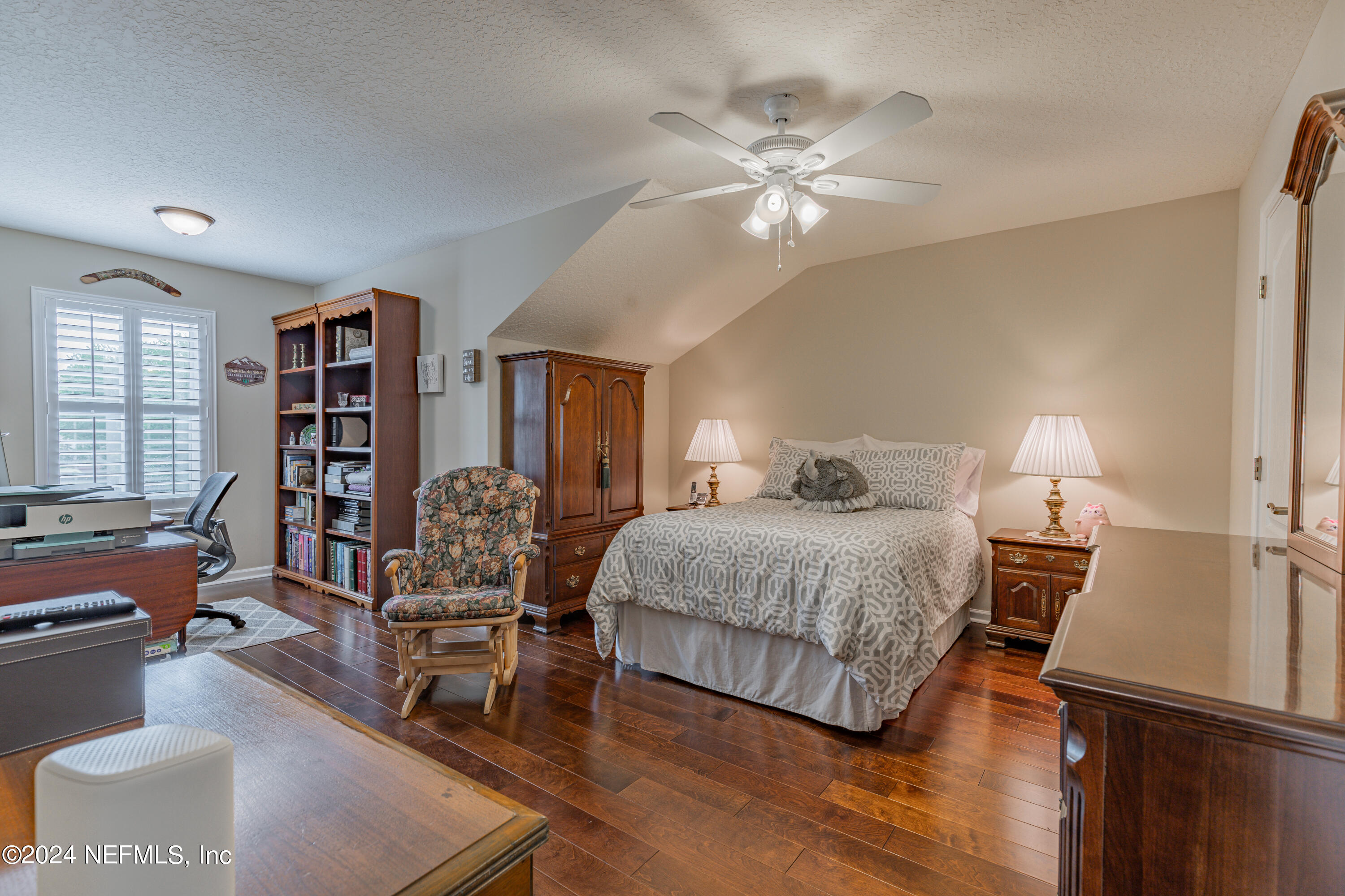 1830 Copper Stone Drive, Unit D Fleming Island, FL 32003 - Photo 28 of 65 a bedroom with a large bed a chandelier and a book shelf