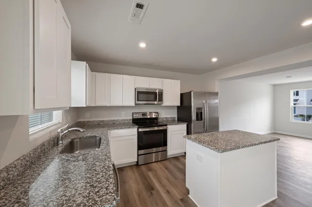 a kitchen with stainless steel appliances granite countertop a sink stove and refrigerator