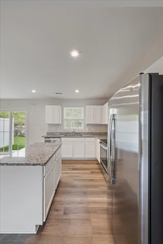 a large kitchen with a center island wooden floor stainless steel appliances and windows