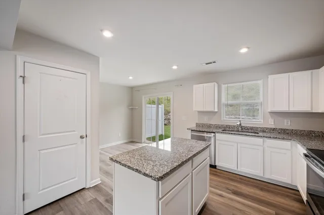 a kitchen with granite countertop cabinets stainless steel appliances a sink and a window
