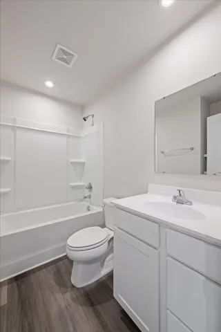 a bathroom with a toilet a sink a mirror a bathtub and vanity