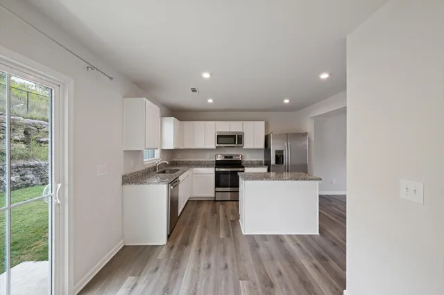 a kitchen with a refrigerator a stove top oven a sink and cabinets with wooden floor