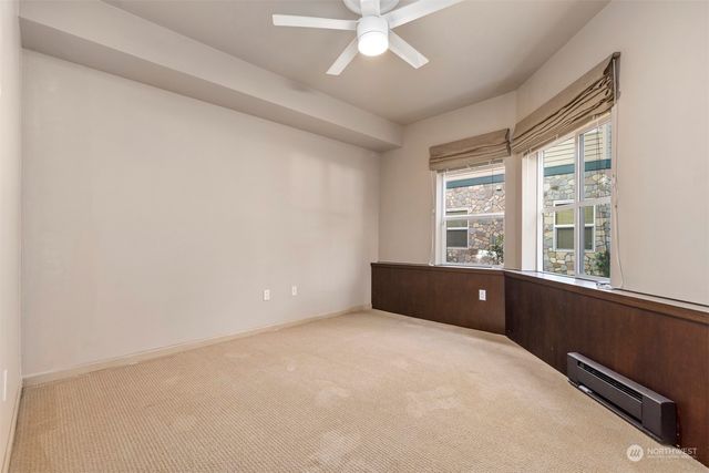 an empty room with chandelier fan and windows