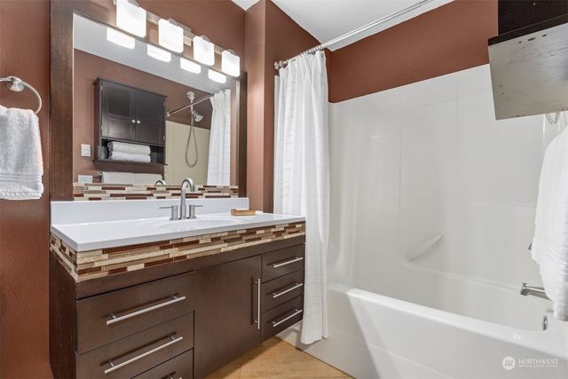 a bathroom with a granite countertop sink a toilet a mirror and bathtub