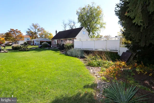 a backyard of a house with table and chairs plants and large tree