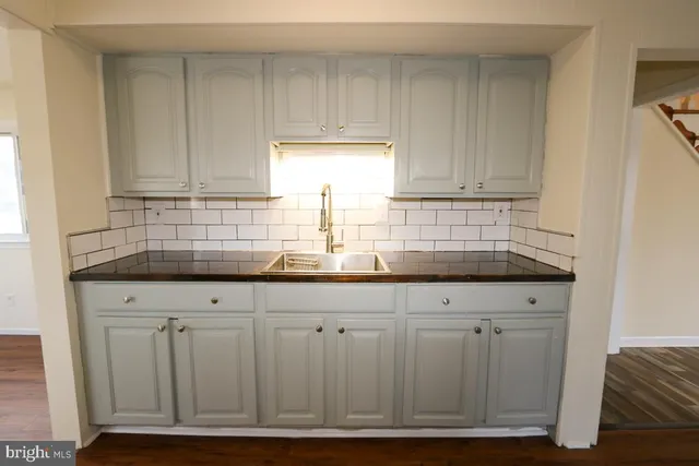 a kitchen with granite countertop white cabinets and sink