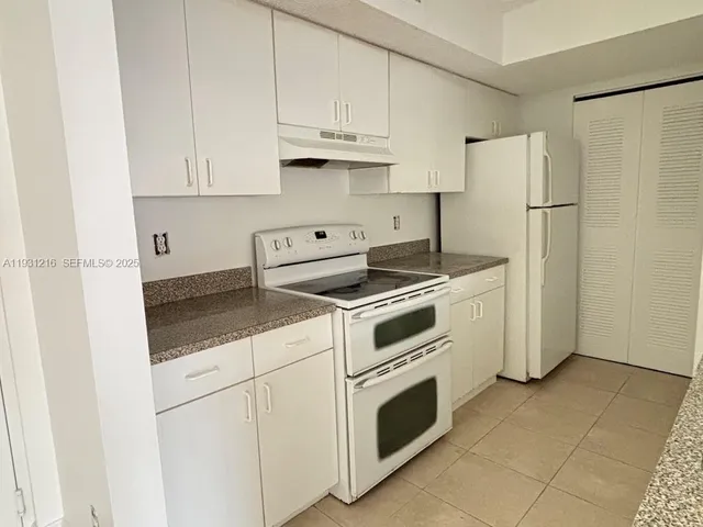 a kitchen with granite countertop white cabinets and white appliances