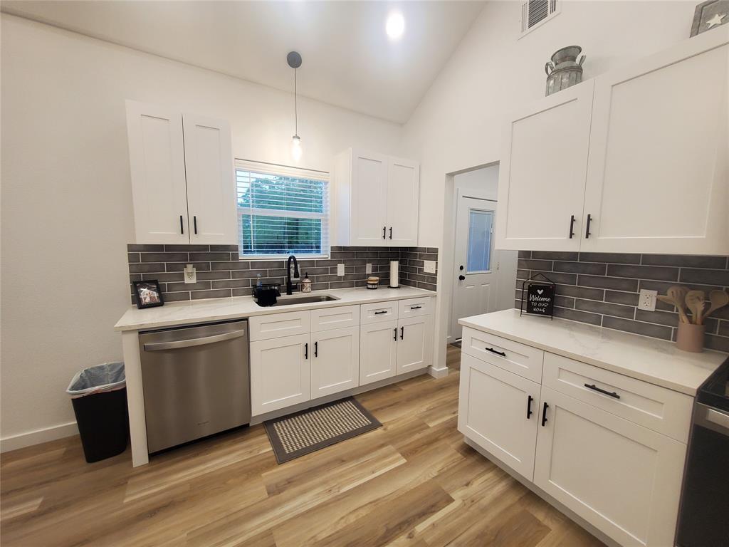 105 Red Tip Lane Brenham, TX 77833 - Photo 35 of 40 a kitchen with stainless steel appliances white cabinets a sink a stove a microwave and wooden floors