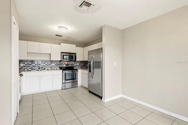 a kitchen with granite countertop white cabinets and stainless steel appliances