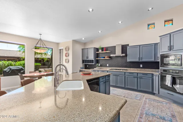a large kitchen with kitchen island a stove a sink a dining table and chairs
