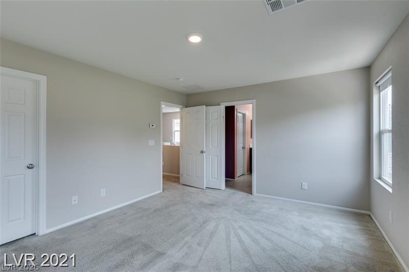 5475 Ordesa Valley Road Las Vegas, NV 89148 - Photo 12 of 35 A well-lit bedroom features plush carpeting and multiple doorways leading to additional spaces.