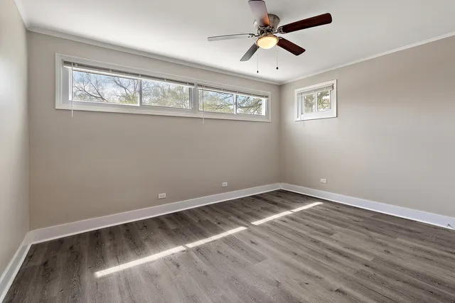 a view of empty room with wooden floor and fan