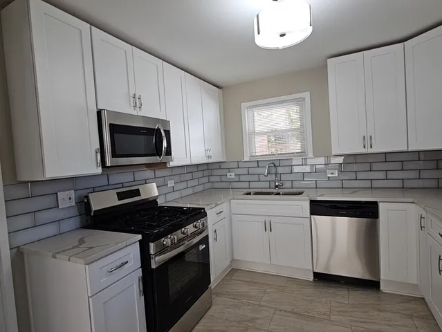 a kitchen with granite countertop white cabinets and black appliances