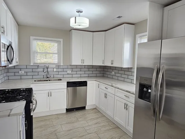 a kitchen with white cabinets appliances and sink