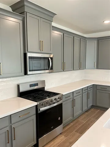 a kitchen with stainless steel appliances granite countertop a sink a stove and a wooden floors