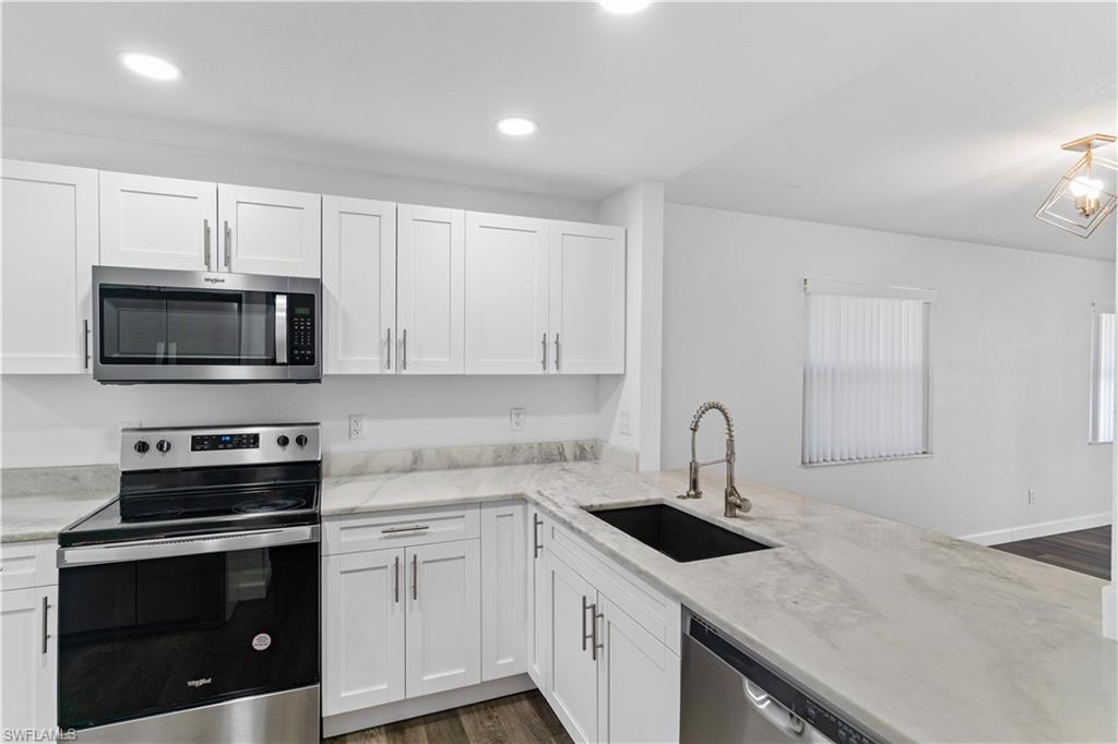 4951 Pepper Circle, Unit A101 Naples, FL 34113 - Photo 4 of 13 a kitchen with granite countertop white cabinets stainless steel appliances and a sink