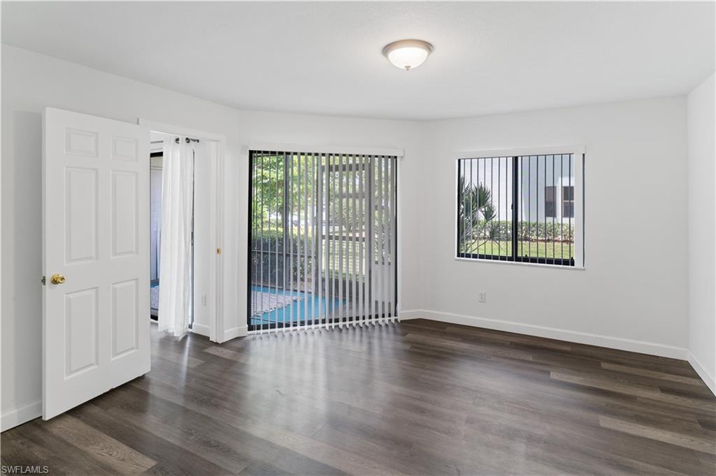 4951 Pepper Circle, Unit A101 Naples, FL 34113 - Photo 6 of 13 an empty room with wooden floor and windows