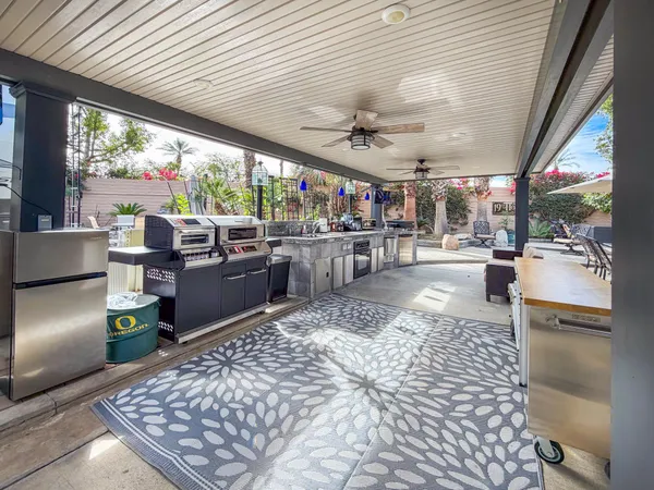 a living room with stainless steel appliances granite countertop furniture a rug kitchen view and a faucet
