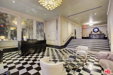 a living room with a black white checkered floor with couches chair and a coffee table