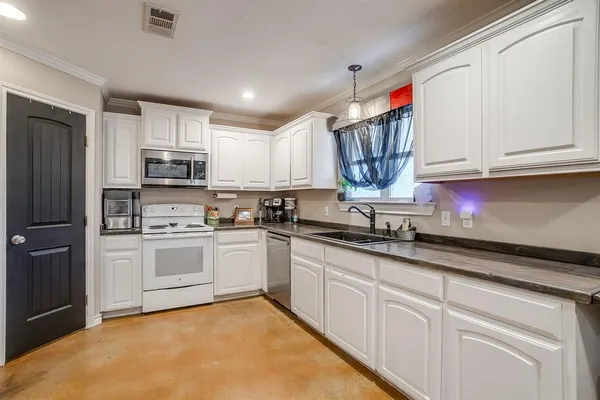 a kitchen with kitchen island granite countertop white cabinets white stainless steel appliances and sink