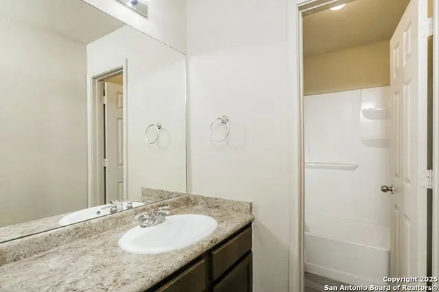 a bathroom with a granite countertop sink and a mirror
